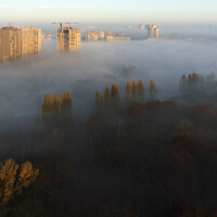 Buy canvas prints of The sun's rays illuminate the morning city through the dense autumn fog by Sergii Petruk