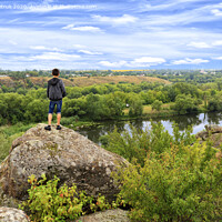Buy canvas prints of A teenager stands on top of a large stone boulder on the banks of the Southern Bug and looks into the distance. by Sergii Petruk
