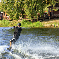 Buy canvas prints of A wakeboarder rushes through the water at high speed along the green bank of the river. by Sergii Petruk