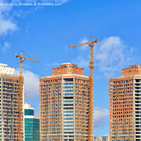 Buy canvas prints of The construction of modern residential skyscrapers with a glass facade and tower cranes against the blue sky. by Sergii Petruk
