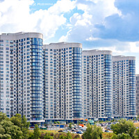 Buy canvas prints of The facades of new residential high-rise buildings against a blue cloudy sky. by Sergii Petruk