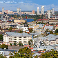 Buy canvas prints of The landscape of the summer city of Kyiv overlooking the old district of Podil with a Ferris wheel and a bell tower with a gilded dome, the Dnipro River and many city buildings. by Sergii Petruk