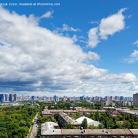Buy canvas prints of A cityscape with a green park in an old residential area of the city and new buildings on the horizon against a bright blue sky with thickening clouds. by Sergii Petruk