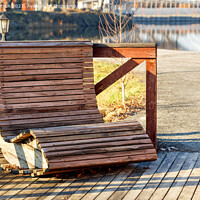 Buy canvas prints of Outdoor furniture, a wooden chair on the river bank is illuminated by the rays of the bright sun against the background of the calm smooth surface of the water in blur. by Sergii Petruk