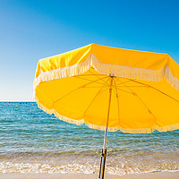 Buy canvas prints of Giant yellow beach umbrella next to the ocean agai by Alexandre Rotenberg