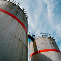 Buy canvas prints of Industrial fuel tanks against a blue sky by Tom Radford