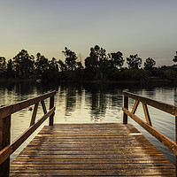 Buy canvas prints of Reddish wooden pier over the lake with calm waters by Juan Ramón Ramos Rivero