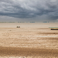 Buy canvas prints of Norfolk coast with storm in the back over the sea boats moored on the sandy beach  by Holly Burgess
