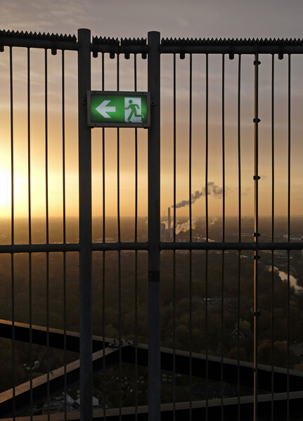 An emergency exit sign with an industrial site in the background Picture Board by Lensw0rld 