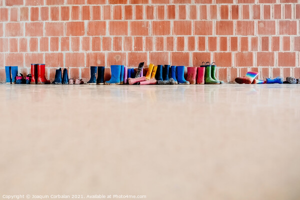 Rubber rain boots on the floor at the entrance to a college clas Picture Board by Joaquin Corbalan