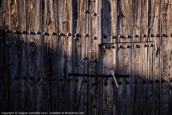 Old and decrepit wooden gate, half lit by the sun, in an unpopul Picture Board by Joaquin Corbalan