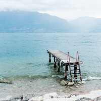 Buy canvas prints of Quiet shore of Lake Garda on a rainy day near the empty jetty. by Joaquin Corbalan