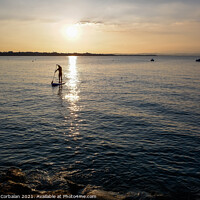 Buy canvas prints of A young man on a paddle surf board approaches the shore of the l by Joaquin Corbalan