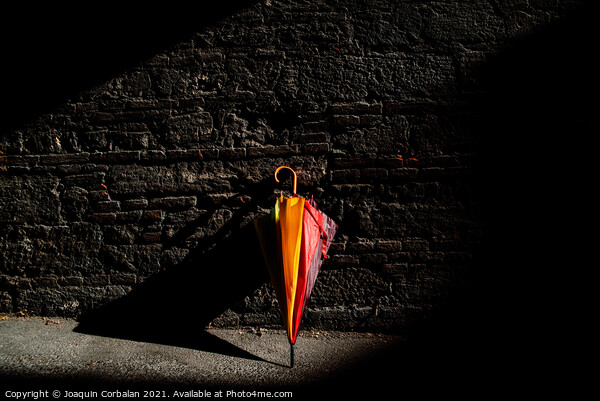 A beautiful colored umbrella rests folded against a brick wall i Picture Board by Joaquin Corbalan