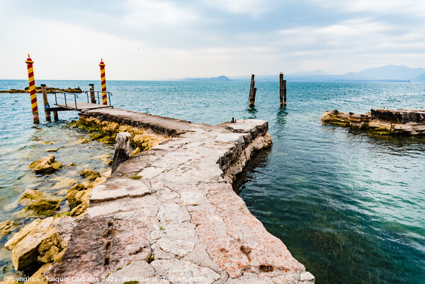 Old stone jetty at the tip of San Vigilio, on Lago di Garda with colorful mooring poles on Picture Board by Joaquin Corbalan