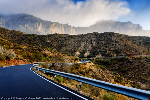 Winding road leads to high mountains with clouds to escape the r Picture Board by Joaquin Corbalan