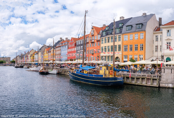 Copenhagen, Denmark - August 8, 2023: The most famous canal in Copenhagen with its quaint colorful houses overlooking the docked sailboats. Picture Board by Joaquin Corbalan