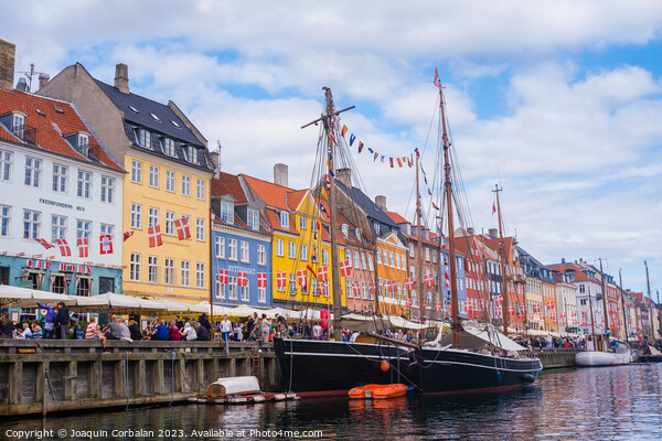 Copenhagen, Denmark - August 8, 2023: The most famous canal in Copenhagen with its quaint colorful houses overlooking the docked sailboats. Picture Board by Joaquin Corbalan