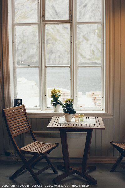 Empty table and antique wooden chairs near a window Picture Board by Joaquin Corbalan
