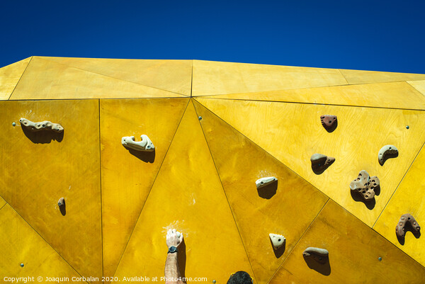 Young man grabs to try climbing on an outdoor climbing wall in a park in Valencia. Picture Board by Joaquin Corbalan