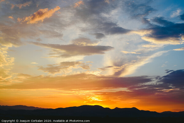 Beautiful sunset with the sun of orange tones behind the mountains and deep blue sky Picture Board by Joaquin Corbalan