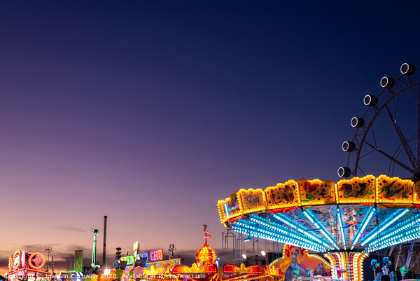 Amusement park at dusk with ferris wheel in the background. Picture Board by Joaquin Corbalan