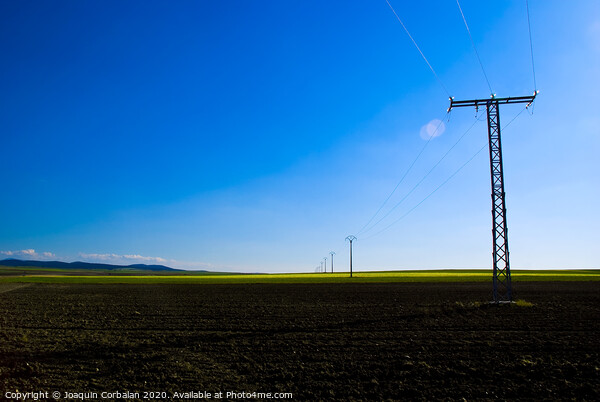 View of a colorful farming field with electricity towers Picture Board by Joaquin Corbalan