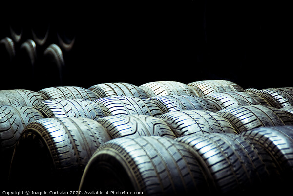 Old tires and racing wheels stacked in the sun Picture Board by Joaquin Corbalan