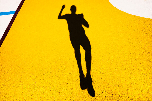 Shadow and silhouette of a man jumping on a yellow painted floor. Picture Board by Joaquin Corbalan
