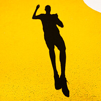 Buy canvas prints of Shadow and silhouette of a man jumping on a yellow painted floor. by Joaquin Corbalan