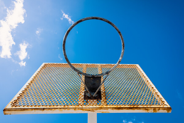 An old basketball basket outside a street with blue sky, copy space for text. Picture Board by Joaquin Corbalan