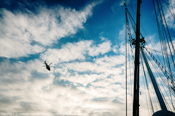  Rescue helicopter flying over a sailboat, seen from the sea. Picture Board by Joaquin Corbalan