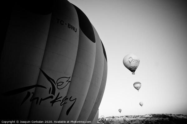 Goreme, Turkey - April 4, 2012: Hot air balloons for tourists flying over rock formations at sunrise in the valley of Cappadocia. Picture Board by Joaquin Corbalan