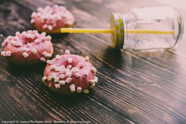 Pair of buns frosted with pink sugar and unhealthy marshsmallows next to a glass jar. Picture Board by Joaquin Corbalan