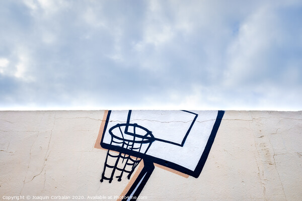 Outdoor basketball court decorated with street graffiti, half with blue sky and clouds in the background. Picture Board by Joaquin Corbalan
