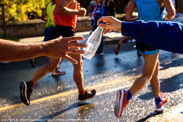 Runner collects a bottle of water to hydrate during a workout. Picture Board by Joaquin Corbalan