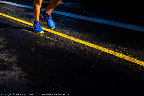 A lonely runner trains on wet asphalt at sunset, copy space. Picture Board by Joaquin Corbalan