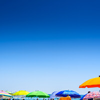 Buy canvas prints of Colorful beach umbrella stuck in the sand surrounded by a group of bathers in summer, near the Mediterranean sea. by Joaquin Corbalan