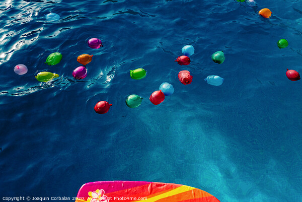 Group of many colorful plastic water balloons floating in the water of a pool to entertain their children on summer vacations. Picture Board by Joaquin Corbalan