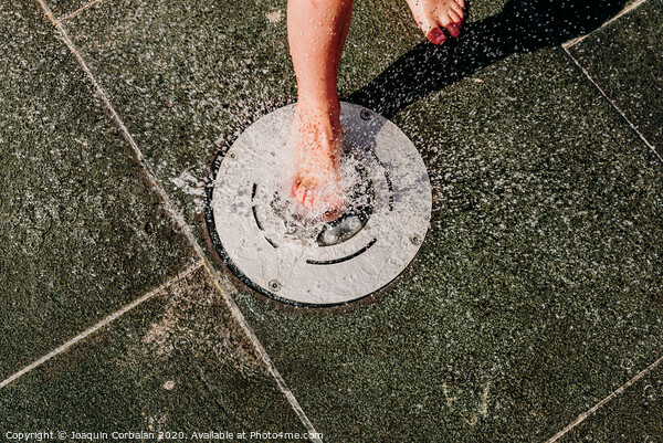 Young barefoot boy running through squirting water in a pool in a spa. Picture Board by Joaquin Corbalan