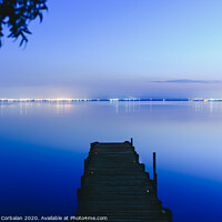 Buy canvas prints of Pier on a lake at sunset with calm water and reflections of relaxing lights. by Joaquin Corbalan