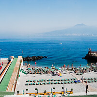 Buy canvas prints of  A beach with sunbathers in Sorrento, with background of unfocused view of Vesuvius volcano. by Joaquin Corbalan
