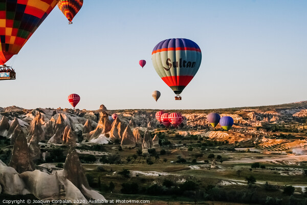 Travelers and tourists flying over mountains at sunset in a colorful aerostat balloon in Goreme, the Turkish cappadocia. Picture Board by Joaquin Corbalan