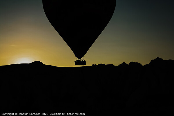 Silhouette of travelers and tourists flying over mountains at sunset in an aerostatic balloon. Picture Board by Joaquin Corbalan