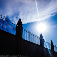 Buy canvas prints of Silhouette against the sun of a high wall and metal fence with an intense blue sky in the background. by Joaquin Corbalan