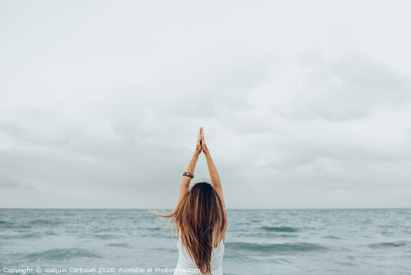 A woman relaxes in front of the sea with her hands up, unfocused background. Picture Board by Joaquin Corbalan