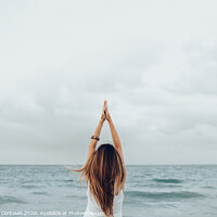 Buy canvas prints of A woman relaxes in front of the sea with her hands up, unfocused background. by Joaquin Corbalan