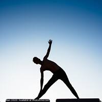Buy canvas prints of Silhouette of a man practicing yoga, isolated against the blue sky. by Joaquin Corbalan