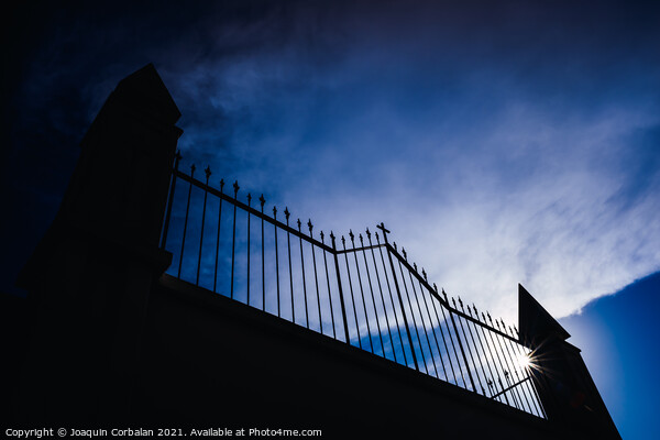 Metal grating of a cemetery with a cross on a white wall, copy s Picture Board by Joaquin Corbalan