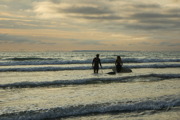 Sunset surfers at Westward Ho! in Devon Picture Board by Tony Twyman